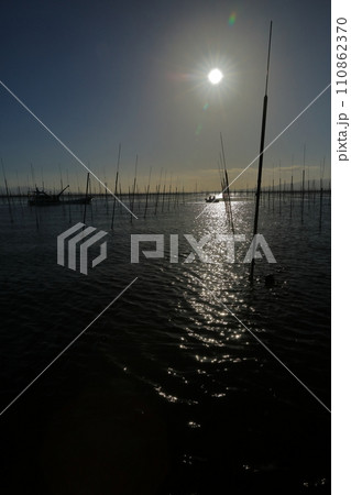 太陽光に輝く有明海の海苔養殖場にに浮かぶ小舟の景色 太陽光に輝く有明海の海苔養殖場にに浮かぶ小舟の景色 110862370