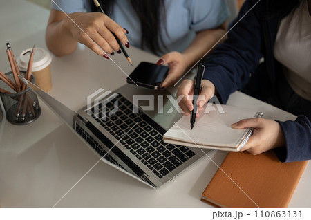 Close-up image of two female office employees are discussing on a project and working in the office. Close-up image of two female office employees are discussing on a project and working in the office. 110863131
