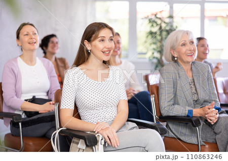 small group of women are sitting in audience, listening to lecture and laugh at amusing case 110863246