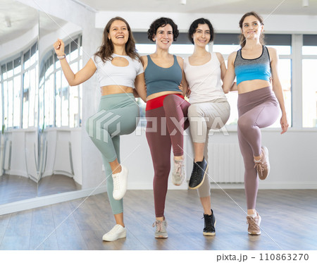 Four happy women performing can-can during dance fitness class 110863270