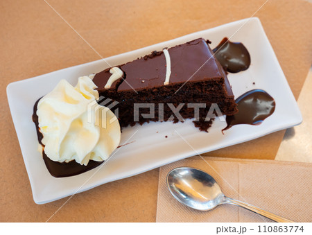 Delicious slice of brownie cake on plate with whipped cream 110863774