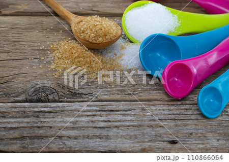 Measuring utensils and spilled sugar on rustic wood 110866064