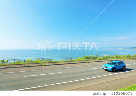 北海道　青空と海沿いの道を走る車 110866073