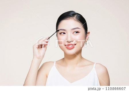 Closeup beautiful woman with eyebrow brush tool on beige 110866607