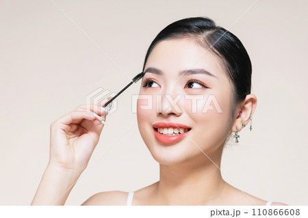 Girl makes makeup. Beautiful woman apply mascara on eyelashes with cosmetic brush Girl makes makeup. Beautiful woman apply mascara on eyelashes with cosmetic brush 110866608