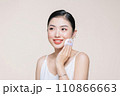 Young asian woman smile looking happy applying makeup with puff makeup on beige background. 110866663