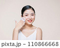 Young asian woman smile looking happy applying makeup with puff makeup on beige background. 110866668