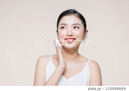 asian woman smile looking happy applying makeup with puff makeup to her face 110866669