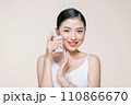 Young adult woman holds a glass of water in her hand near face 110866670