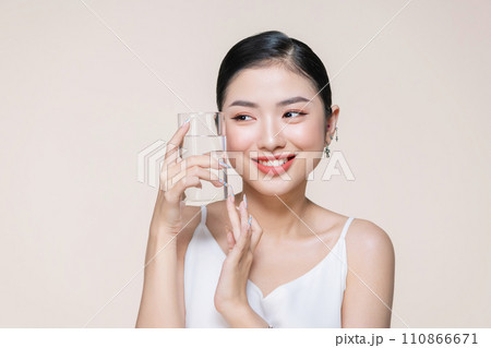 beautiful young asian woman with closed eyes holding glass of clear water near face 110866671
