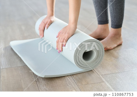 ヨガマットを広げる女性の手元 110867753