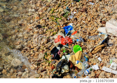 Garbage on a bank of ocean. Pollution of sea, ocean water with waste, plastics garbage. Concept of pollution of ocean, sea and river coastline with plastic trash Garbage on a bank of ocean. Pollution of sea, ocean water with waste, plastics garbage. Concept of pollution of ocean, sea and river coastline with plastic trash 110870389