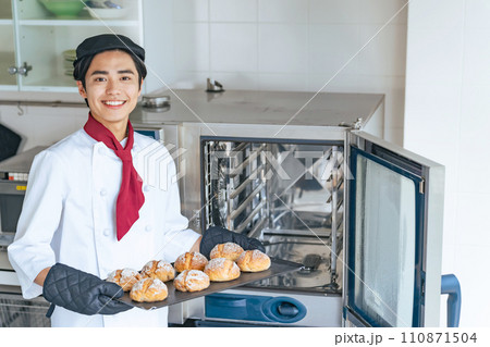 オーブンからパンを取り出すパン職人 110871504