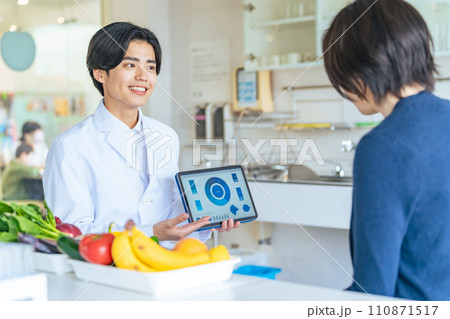 タブレット画面を見せて説明する白衣の男性 110871517