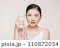 beautiful young asian woman holding glass of clear water near face 110872034