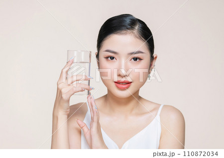 beautiful young asian woman holding glass of clear water near face 110872034