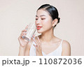 Young adult woman holds a glass of water in her hand near face 110872036