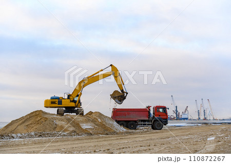 Yellow excavator working on construction site. The road construction. Yellow excavator working on construction site. The road construction. 110872267