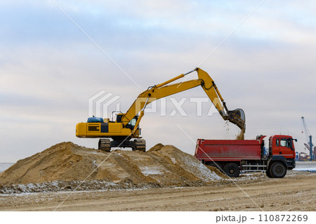 Yellow excavator working on construction site. The road construction. Yellow excavator working on construction site. The road construction. 110872269