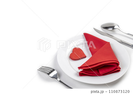 White plate with silverware of fork, knife, and spoon with red heart and red napkin 110873120
