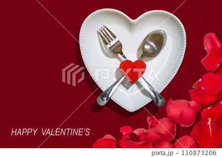 Heart plate with silverware of spoon and fork with a red heart and rose petal Heart plate with silverware of spoon and fork with a red heart and rose petal 110873206