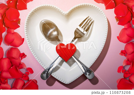 Heart plate with silverware of spoon and fork with a red heart and rose petal 110873208