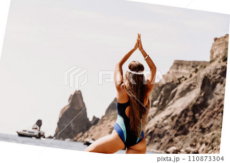 Woman beach vacation photo. A happy tourist in a blue bikini enjoying the scenic view of the sea and volcanic mountains while taking pictures to capture the memories of her travel adventure. 110873304