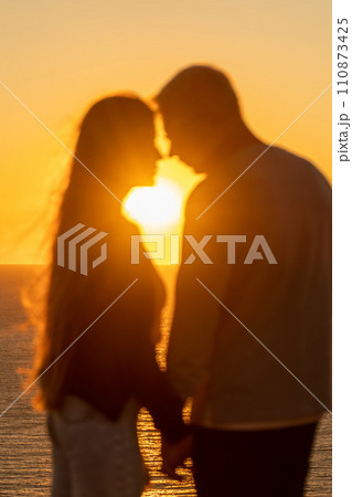 At sunset, a couple shares a tender embrace on the beach, basking in the tranquility of their holiday and the beauty of nature. 110873425