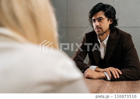 Back view of unrecognizable businesswoman having meeting with serious male colleague in office. Concept of company CEO negotiating with business partners, involved in dispute at briefing. Back view of unrecognizable businesswoman having meeting with serious male colleague in office. Concept of company CEO negotiating with business partners, involved in dispute at briefing. 110873510