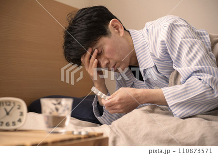 寝る前に薬を飲む男性　不眠症　睡眠薬　 110873571