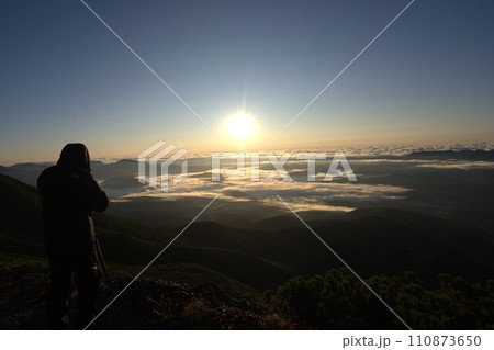 山頂から朝日を撮影するカメラマン 110873650