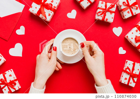 Flat lay of heart shaped cup of black coffee in the hands of women on colored background with copy space top view. Valentine day and holiday concept 110874030