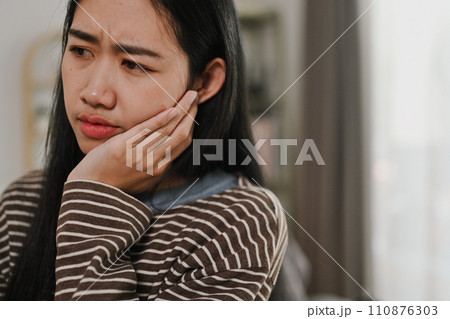 Young woman suffering acute toothache, touching her cheek with painful expression. Dental Care concept Young woman suffering acute toothache, touching her cheek with painful expression. Dental Care concept 110876303