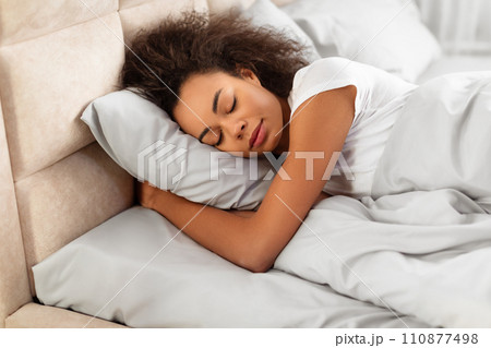 African American Lady Sleeping Peacefully Embracing Pillow In Modern Bedroom African American Lady Sleeping Peacefully Embracing Pillow In Modern Bedroom 110877498