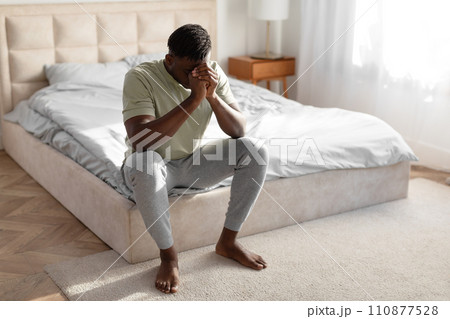 Desperate African Man Covering Face Experiencing Mental Issues In Bedroom Desperate African Man Covering Face Experiencing Mental Issues In Bedroom 110877528