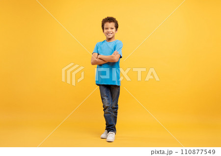 Confident latin boy with arms crossed in blue shirt, yellow background Confident latin boy with arms crossed in blue shirt, yellow background 110877549