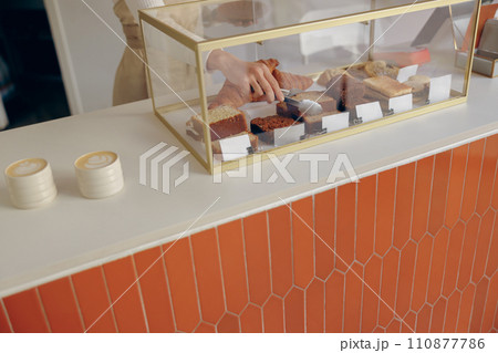 Close-up of female waitress hands putting a delicious dessert on a plate standing behind bar counter Close-up of female waitress hands putting a delicious dessert on a plate standing behind bar counter 110877786