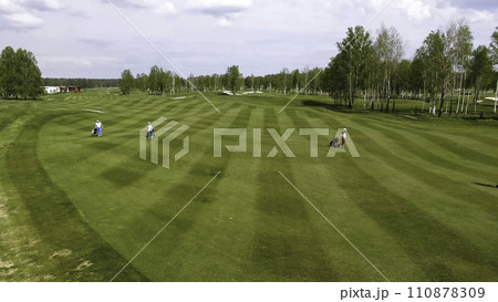Aerial view Golf course. Golfers walking down the fairway on a course with golf bag and trolley Aerial view Golf course. Golfers walking down the fairway on a course with golf bag and trolley 110878309