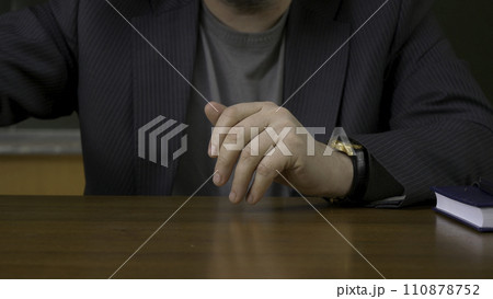 Teacher sits at the table with the record book Teacher sits at the table with the record book 110878752