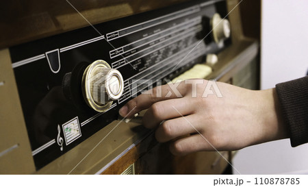 Close-up of man's hand rotating the knob on the old radio. Concept. Vintage technology 110878785