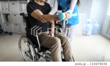 Man on wheelchair works out his hand with dumbbell 110879036