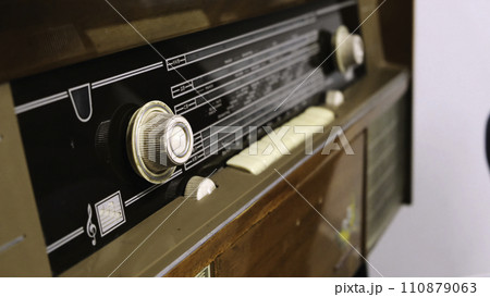 Close-up of man's hand rotating the knob on the old radio. Concept. Vintage technology 110879063