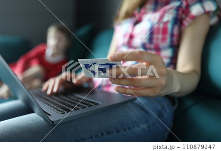 Mom is sitting on couch with laptop and credit card 110879247