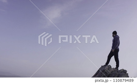 Man on top of the mountain. A young, athletic man stands on a high rock Man on top of the mountain. A young, athletic man stands on a high rock 110879489
