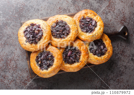 Cebularz lubelski is a round-shaped flatbread topped with diced red onion and poppy seed close-up on a wooden board. Horizontal top view Cebularz lubelski is a round-shaped flatbread topped with diced red onion and poppy seed close-up on a wooden board. Horizontal top view 110879972