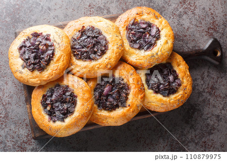 Cebularz is a wheat dough pancake in Polish and Jewish cuisine topped with diced onion and poppy seed close-up on a wooden board. Horizontal top view Cebularz is a wheat dough pancake in Polish and Jewish cuisine topped with diced onion and poppy seed close-up on a wooden board. Horizontal top view 110879975