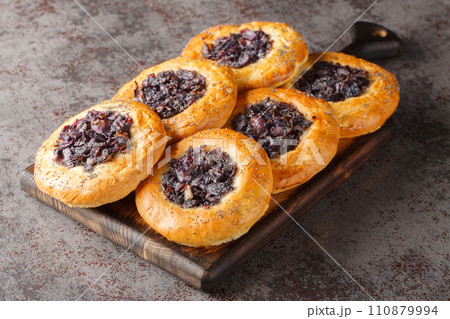 Cebularz lubelski is a round-shaped flatbread topped with diced red onion and poppy seed close-up on a wooden board. Horizontal 110879994