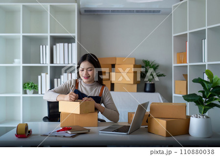 Young woman working online ecommerce shopping at her shop. Young woman sell prepare parcel box of product for deliver to customer. Online selling, ecommerce. Selling products online 110880038