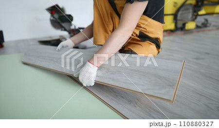 Repairman replaces laminate panels floor apartment 110880327