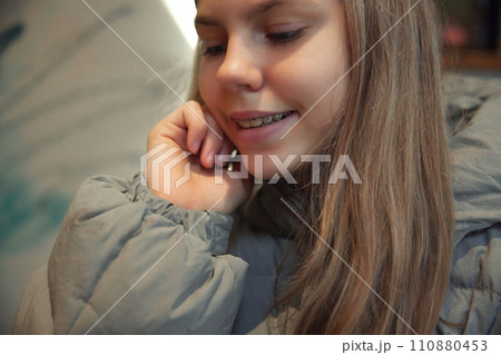 Close-up portrait of smiling teenage girl with braces, touching her hair against blurred background. Selective focus. Close-up portrait of smiling teenage girl with braces, touching her hair against blurred background. Selective focus. 110880453